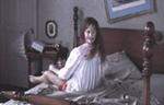 Foto da menina do filme O exorcista sentada na cama com sua cabeça virada para trás